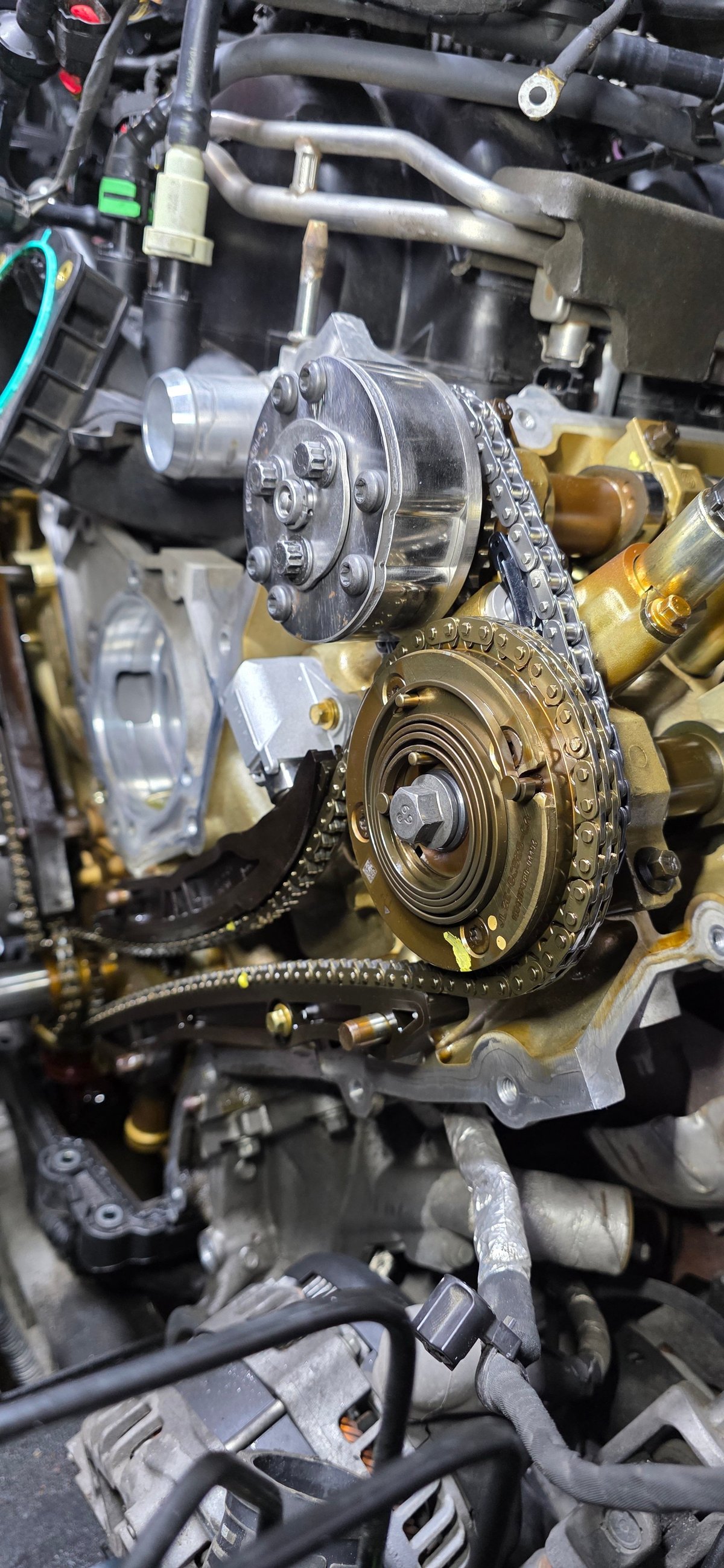 Close-up of car engine timing chain and pulley system with metal components and mechanical parts visible